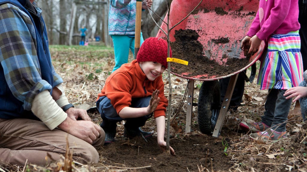 Boy plants a tree during GFAC April Vacation Camp