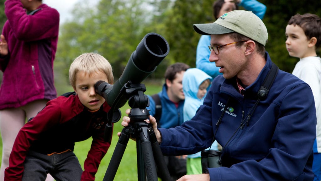 Staff Naturalist Doug Hitchcox helps a boy view wildlife through a scope