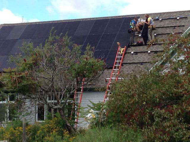 ReVision employees installing solar panels on the roof of the Fields Pond Audubon Center. Photo: David Lamon.